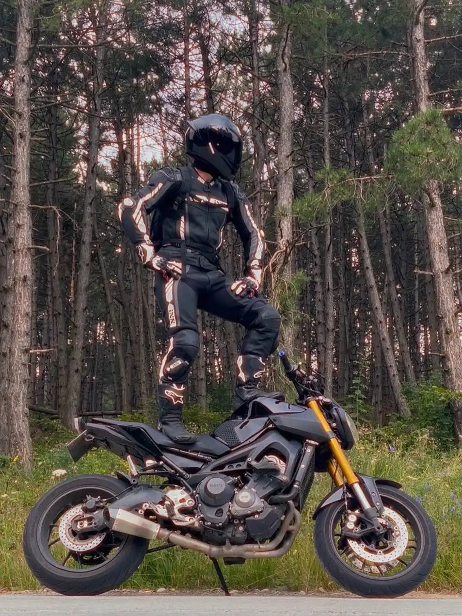 Nikita in riding gear with his motorcycle in a forest